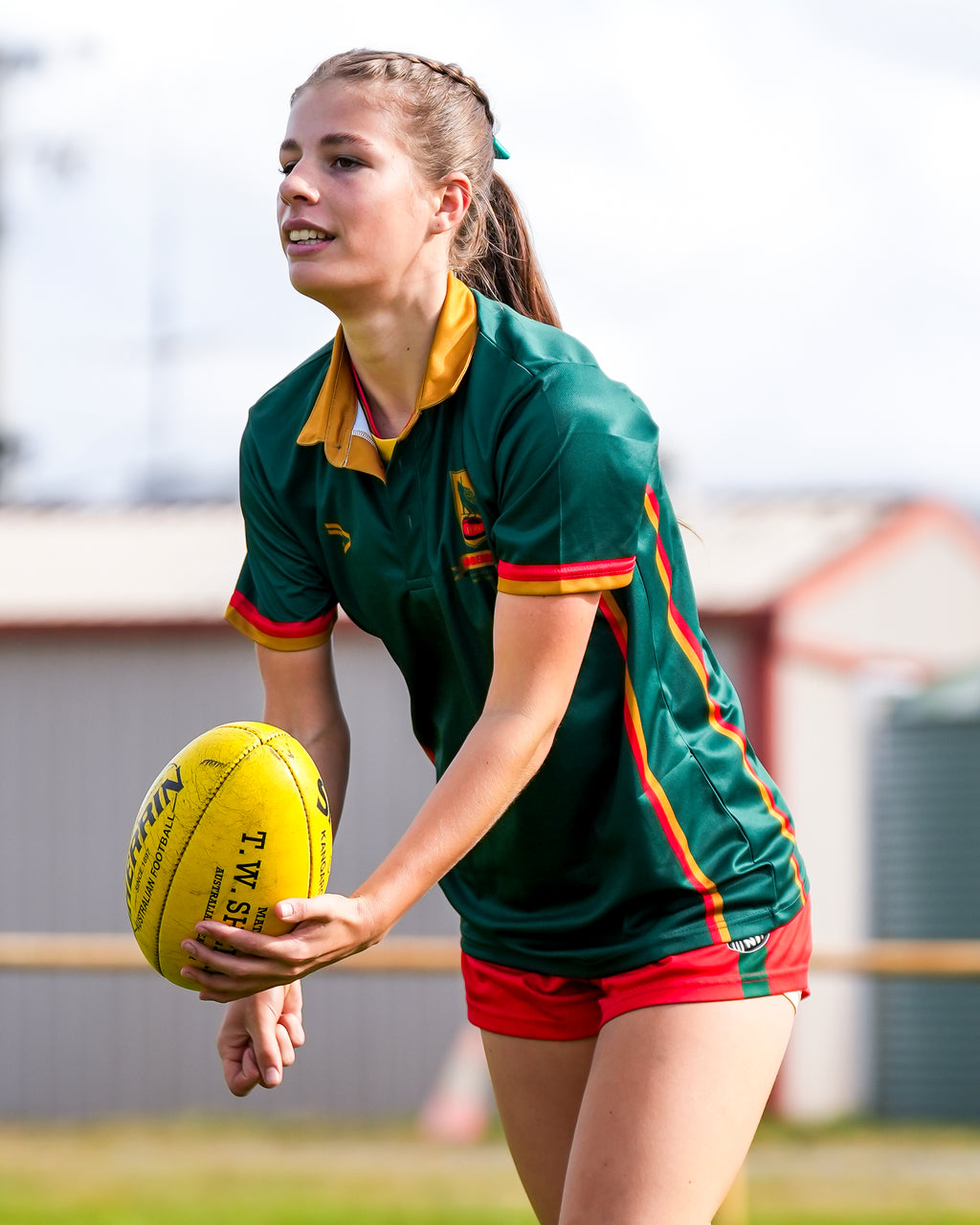 Taj Richardson in sports uniform holding a yellow football on a grassy field