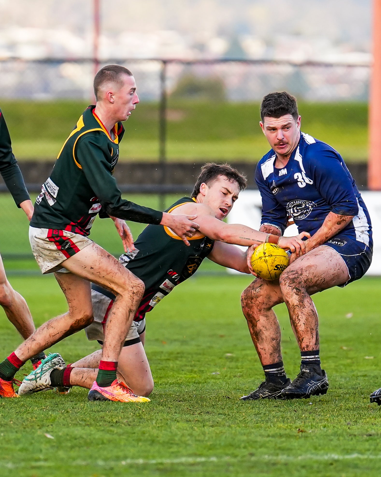 Three football players contesting for the ball during a match in the 2025 season