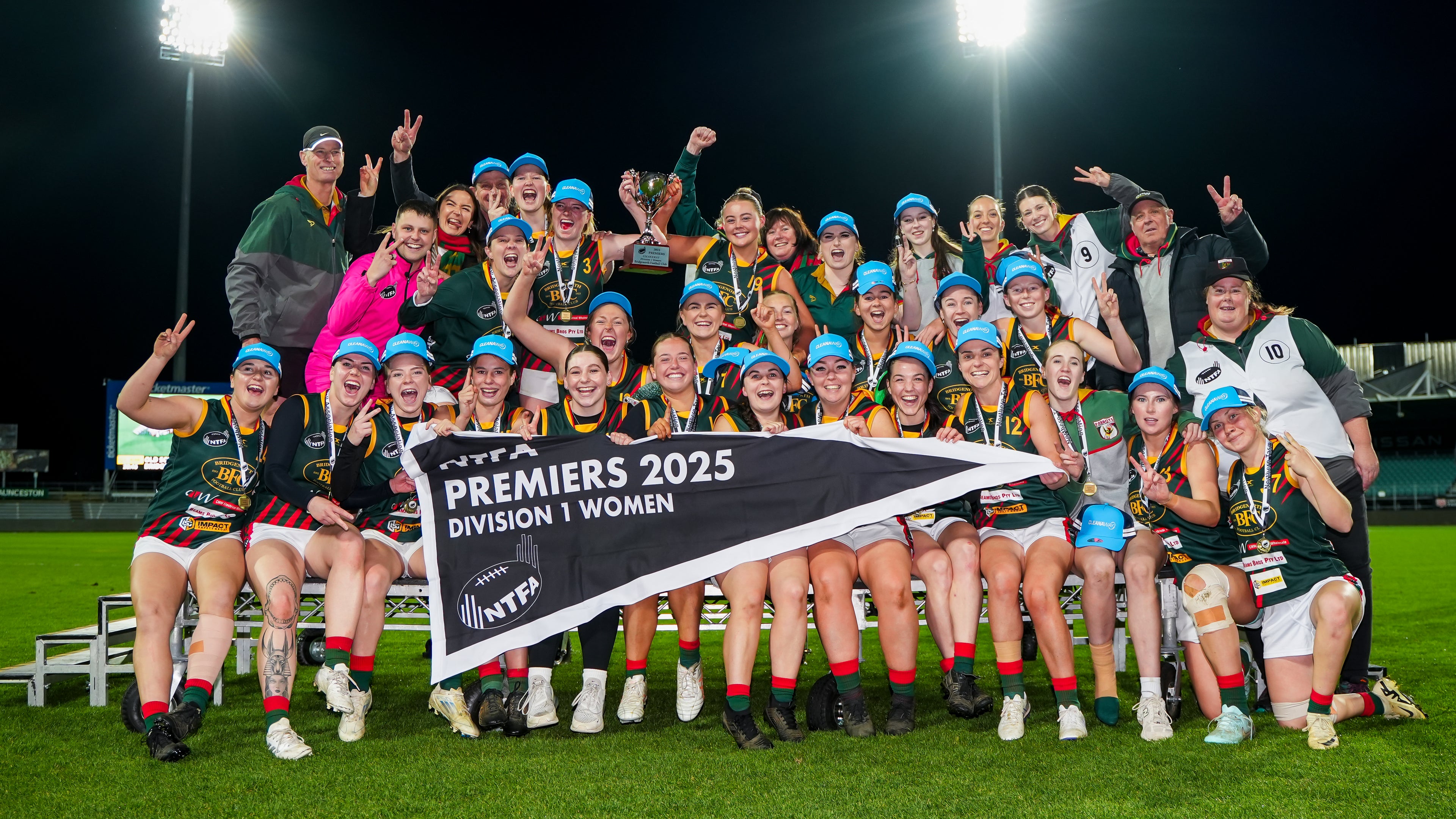 Group of the Bridgenorth Football Club Women's  team celebrating with a 2025 premiers banner at UTAS stadium