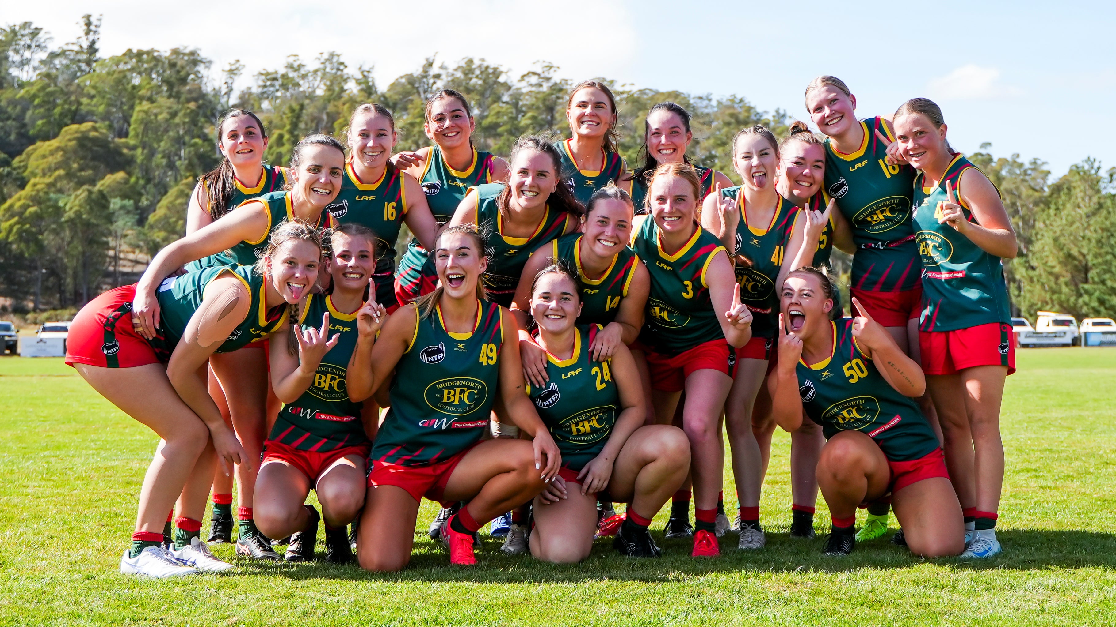 Group of the Womens team posing on a football field after winning