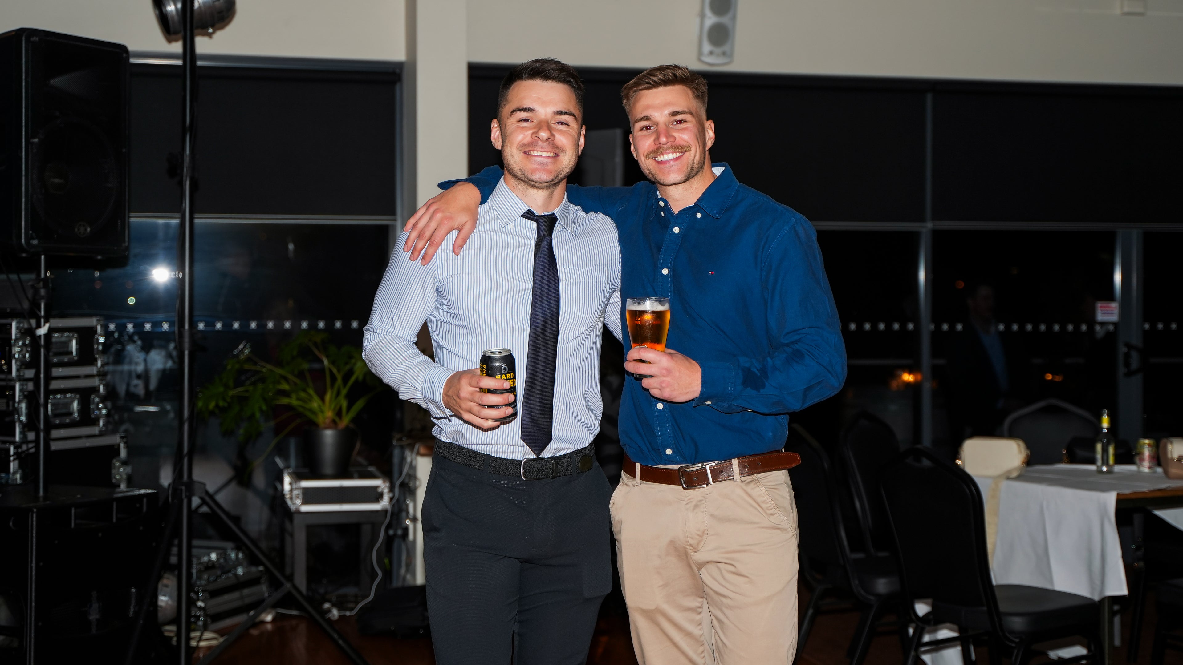 Matt and Brad standing together at the ball, holding drinks.