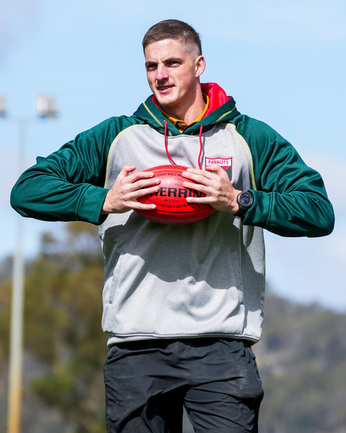 Person holding a red sports ball outdoors with a blurred background