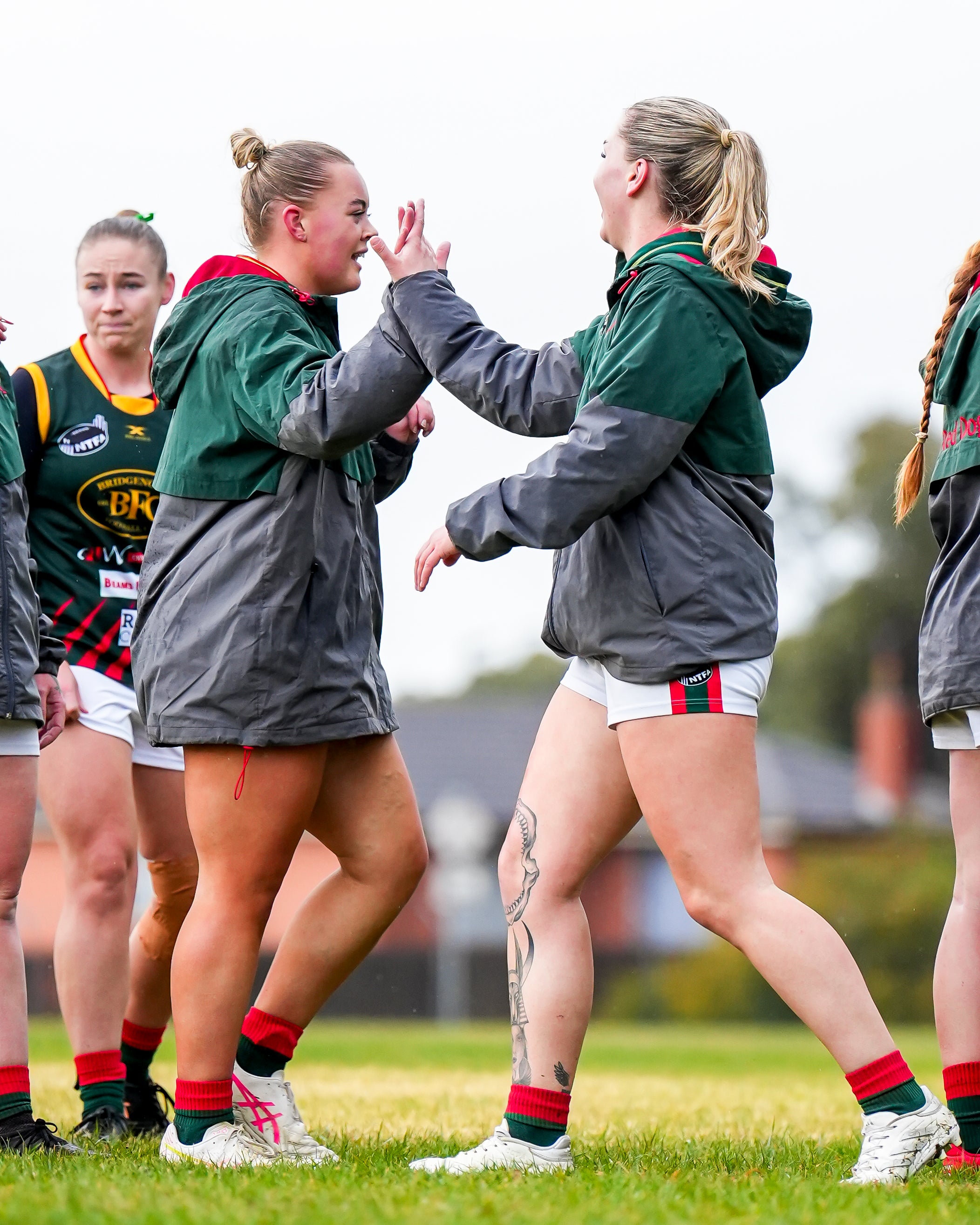 Two Bridgenorht players high-fiving on the football field with other players in the background.