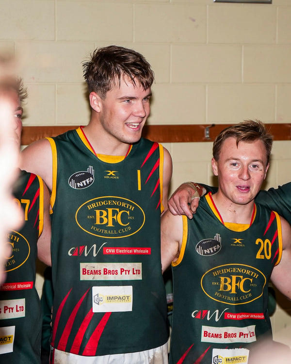 Two men wearing Bridgenorth BFC sports jerseys in a locker room setting.